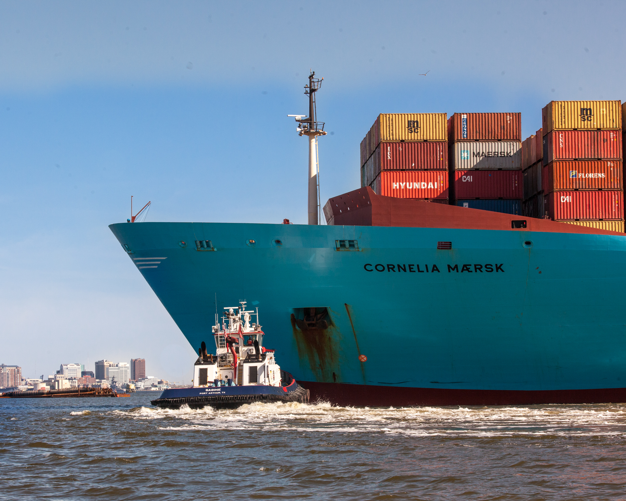 photograph by Bryan Hatchett, copyright, Bryan Hatchett, color photograph, Tugboat Sabine, leased to McAllister Towing &amp; Transportation, pushes outbound container ship Cornelia Maersk into the Elizabeth River channel adjacent to the wharf at Virginia International Gateway on the Portsmouth, VA shoreline. Off the ship's bow, downtown Norfolk is in the distance.