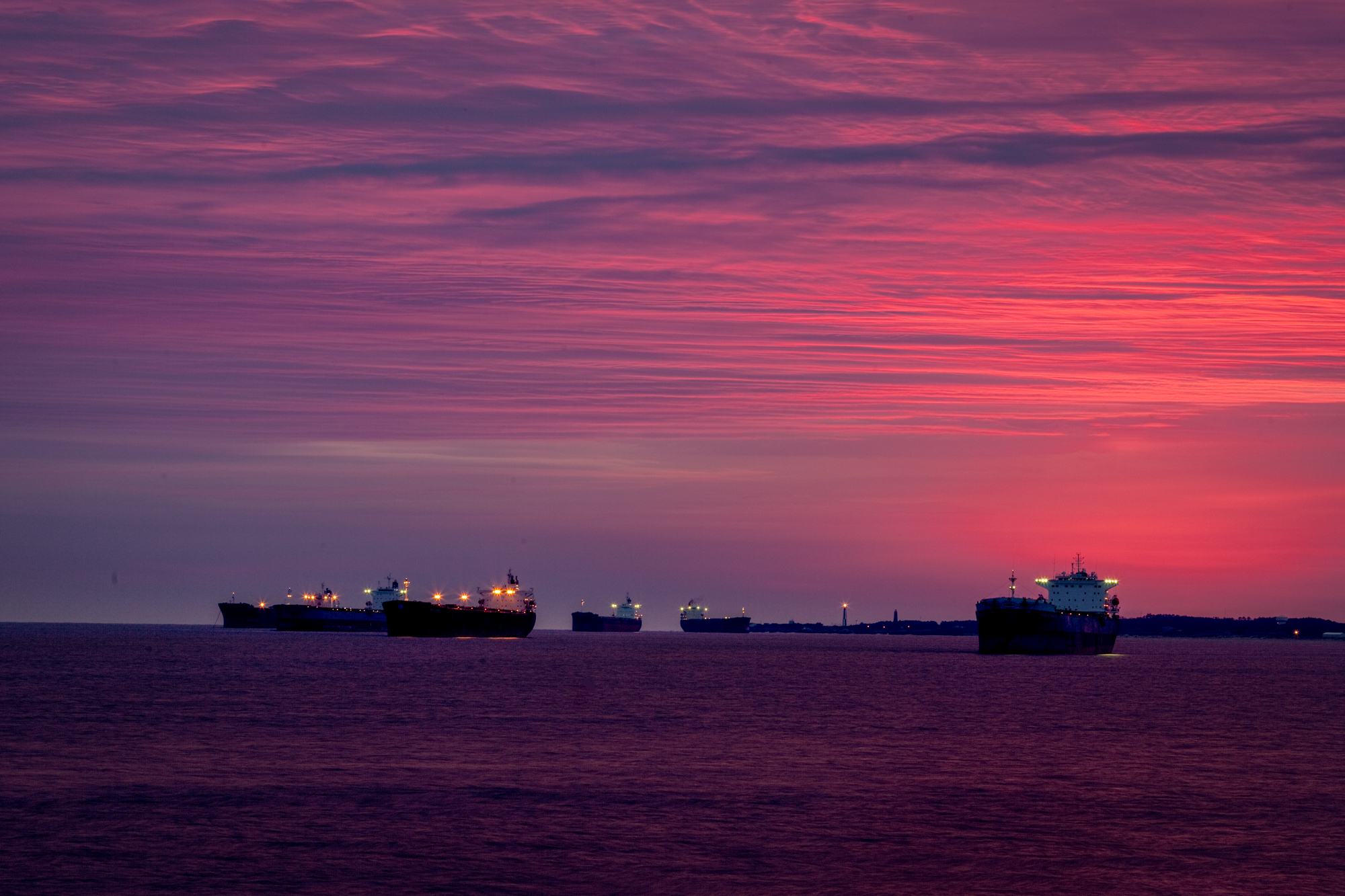 photograph by Bryan Hatchett, copyright, Bryan Hatchett, color photograph, Just before dawn, freighters lie at anchor east of Hampton Roads in lower Chesapeake Bay. Cape Henry Lighthouse is in the distance. Photographed fro the Chesapeake Bay Bridge-Tunnel, Virginia Beach, Virginia